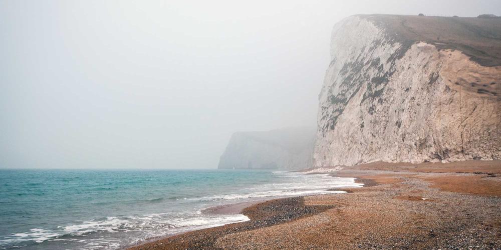 Futuristic arcade lounge with neon pink strip lighting along dark walls, sleek gaming stations with glowing peripherals, atmospheric haze, cinematic composition